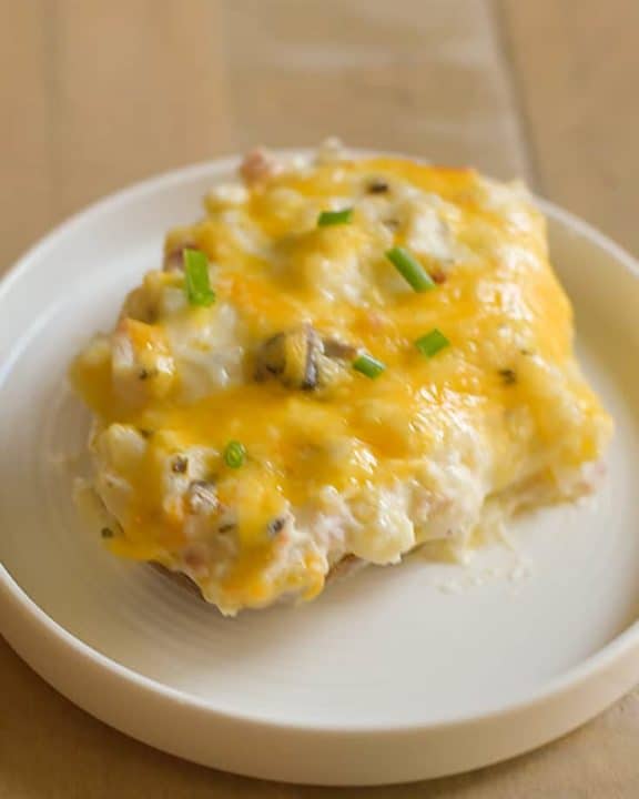 A twice baked potato with mushrooms, sour cream, and cheese