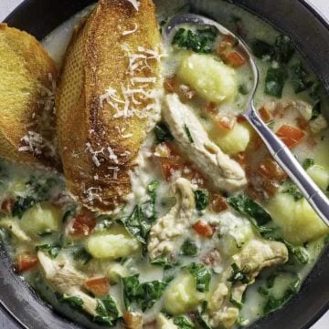 a bowl of homemade Macaroni Grill chicken Toscana soup and 2 pieces of toasted bread in it.