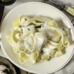 Alfredo sauce over pasta on a plate.