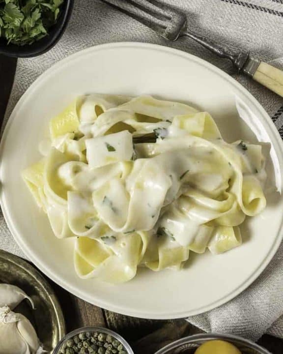 Alfredo sauce over pasta on a plate.