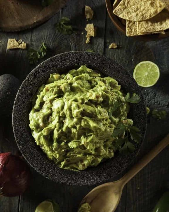 A bowl of guacamole made with fresh avocados and canned tomatoes.