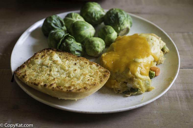 Tuna stuffed crescent roll casserole with garlic bread and Brussels sprouts on a plate