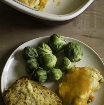 tuna stuffed crescent roll casserole on a plate with bread and Brussels sprouts