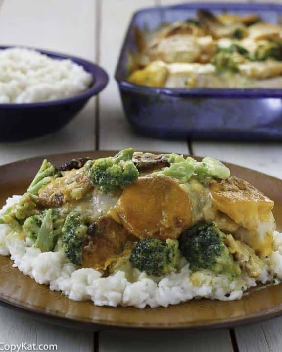 Homemade copycat Cracker Barrel Broccoli Cheddar Chicken Casserole and rice on a brown plate.