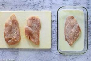Raw chicken breasts being breaded to make Cracker Barrel Sunday Chicken.