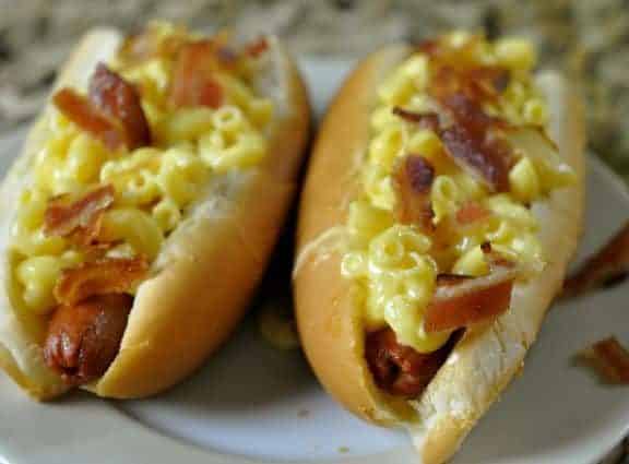 two hot dogs topped with truffle macaroni and cheese and bacon