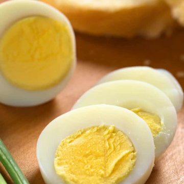 Slices of hard boiled eggs on a wood cutting board