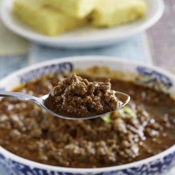 A spoon of copycat Chilis Original style chili over a bowl of it.