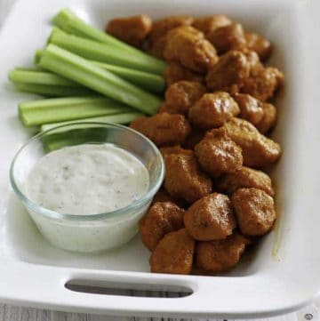 Boneless Buffalo Chicken Bites on a platter with blue cheese dressing and celery sticks