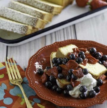 Homemade copycat Sara Lee Pound Cake with fruit in front of the cake on a platter.