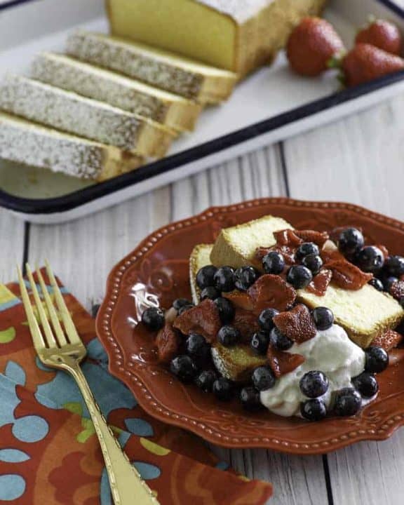 Homemade copycat Sara Lee Pound Cake with fruit in front of the cake on a platter.
