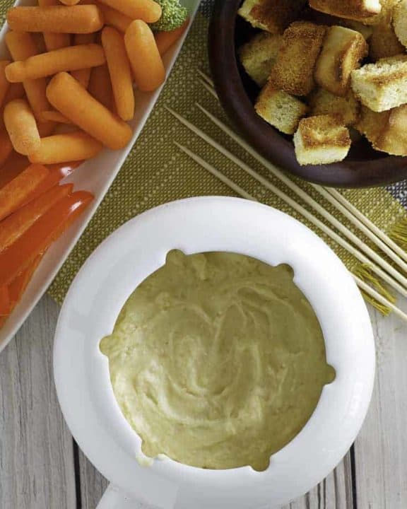 Homemade Melting Pot Traditional Swiss Fondue with vegetables and bread cubes.