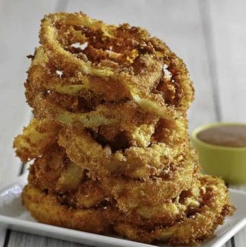 Homemade copycat Red Robin Onion Rings stacked on a white plate.