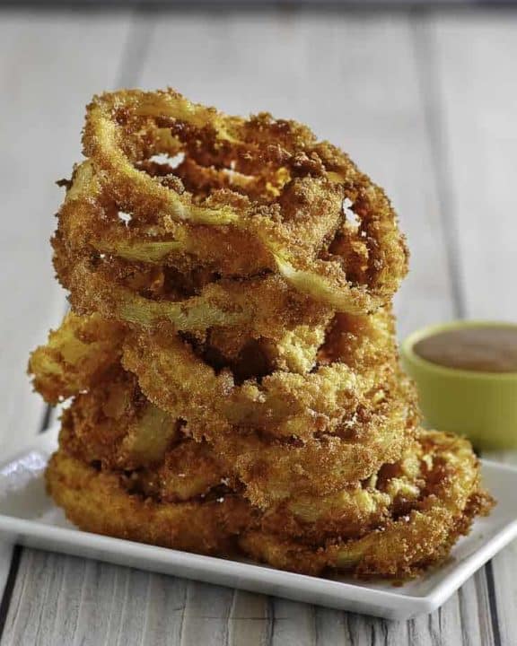 Homemade copycat Red Robin Onion Rings stacked on a white plate.