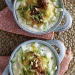 two bowls of baked potato soup with toppings of cheese and bacon