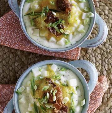 two bowls of baked potato soup with toppings of cheese and bacon