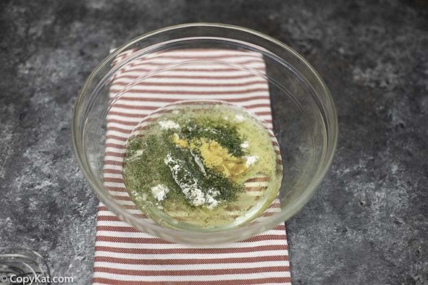 A bowl of vegetable oil, dry Ranch salad dressing mix, and garlic powder.