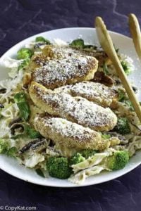 Parmesan crusted chicken tenders and pasta on a plate.