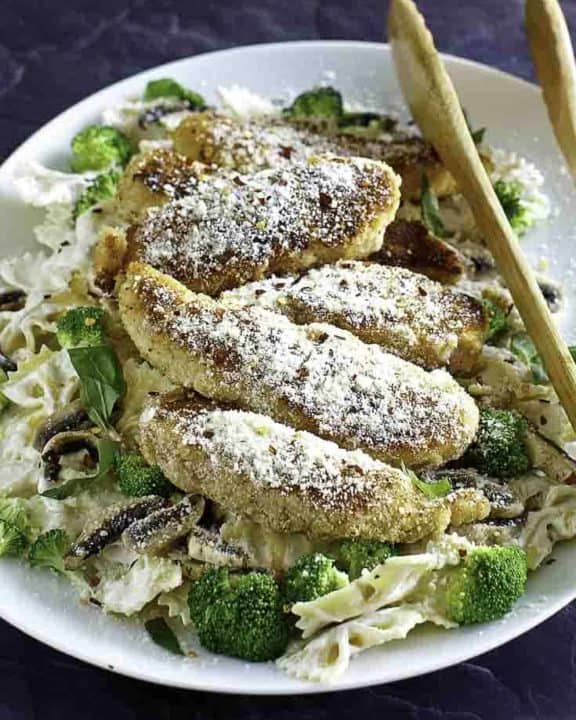 Parmesan crusted chicken tenders and pasta on a plate.