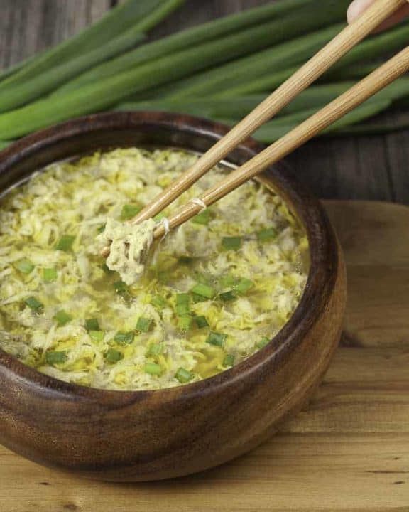 A bowl of egg drop soup with green onions.