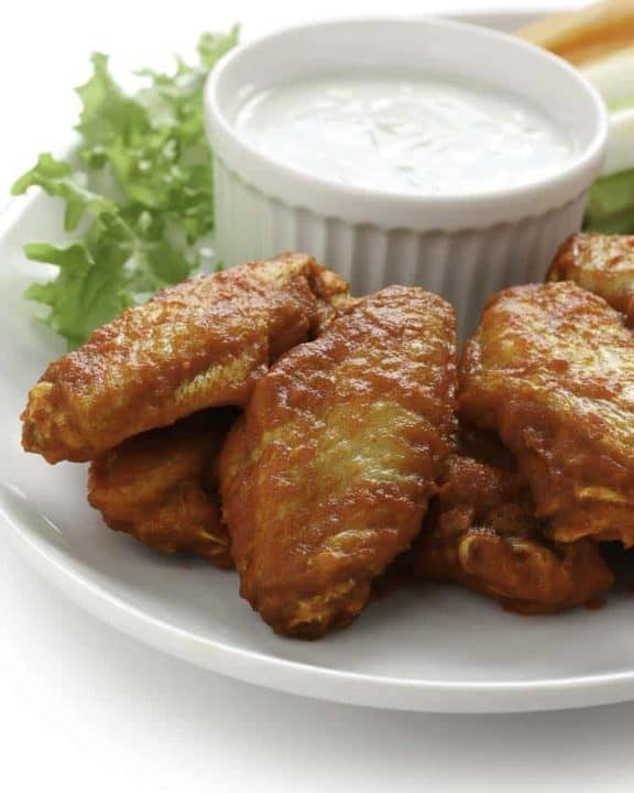 Homemade Junior's Buffalo wings and blue cheese salad dressing on a plate