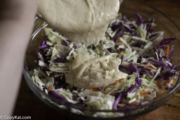 Pouring coleslaw dressing on shredded cabbage