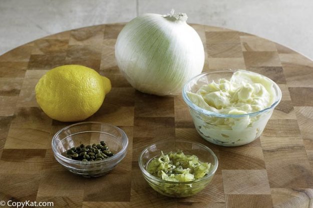 Ingredients to make homemade tartar sauce: mayonnaise, dill pickles, capers, lemon, and onion.