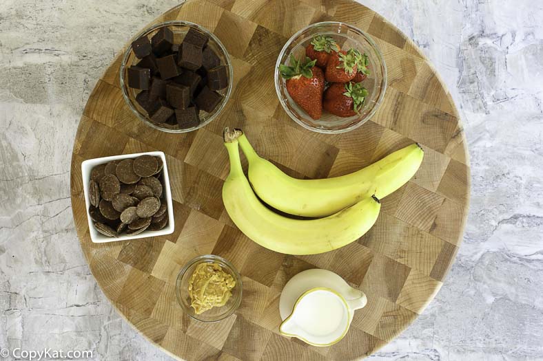 Ingredients for chocolate fondue recipe: milk chocolate, cream, fruit, and more 