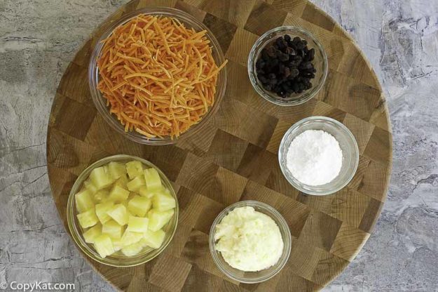 Ingredients to make carrot raisin salad. Shredded Carrots, pineapple, powdered sugar, mayonnaise, and raisins.