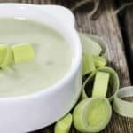 a bowl of potato leek soup with a few cut up leeks