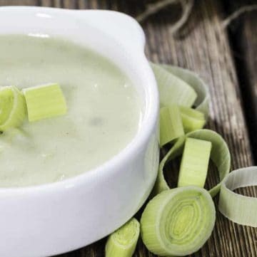a bowl of potato leek soup with a few cut up leeks