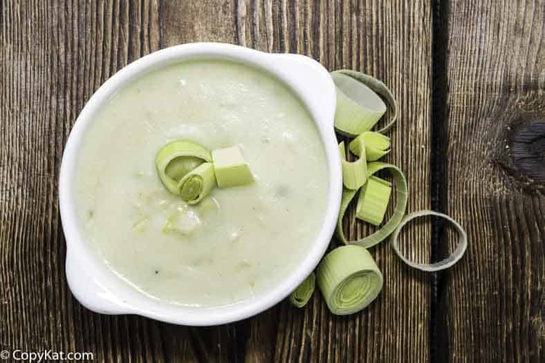 A bowl of cream of potato and leek soup on a wooden board