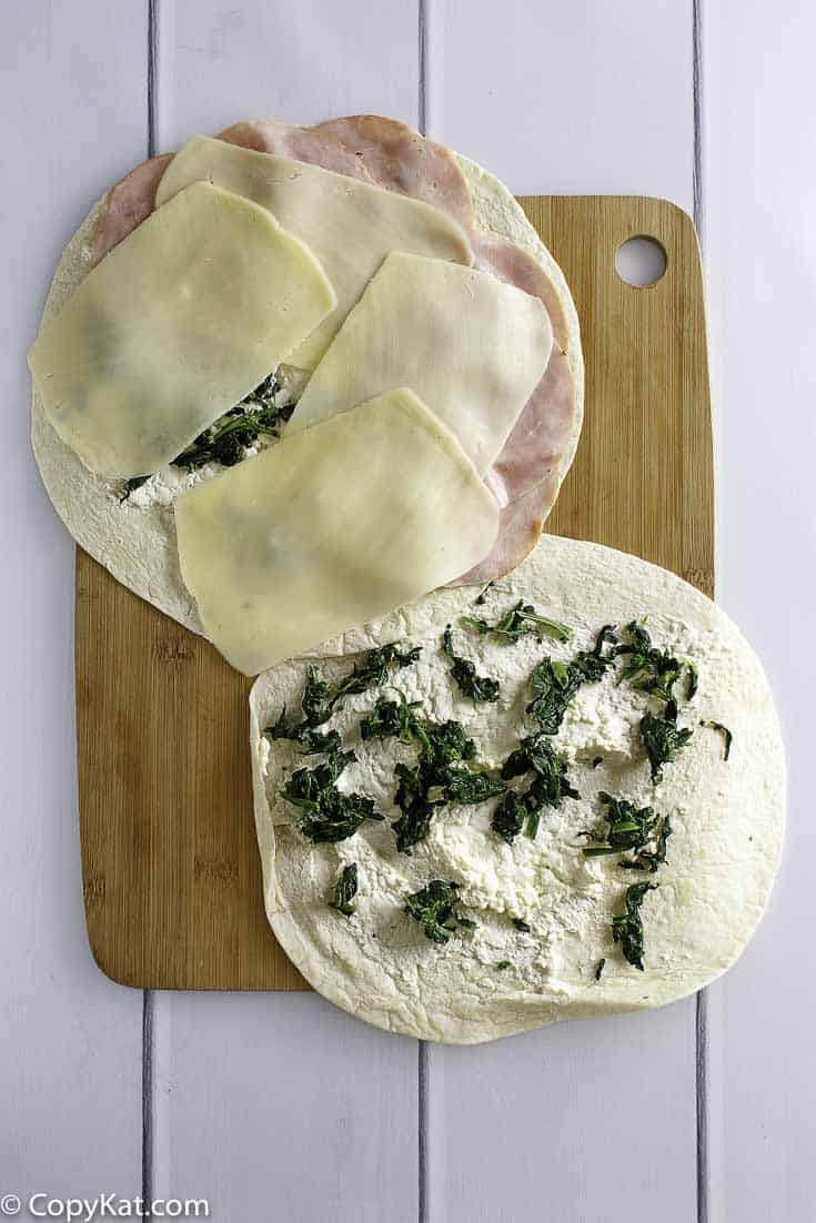 layering ham, cheese, and spinach on tortilla to make pinwheels