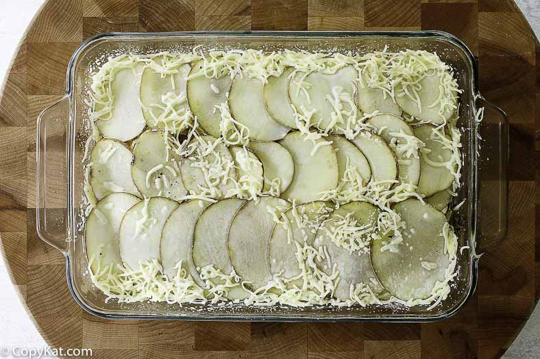 sliced potatoes and shredded cheese in a baking dish