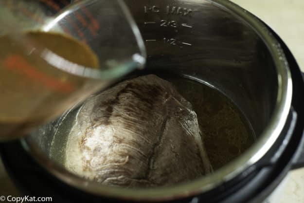 pouring seasoning mix over roast