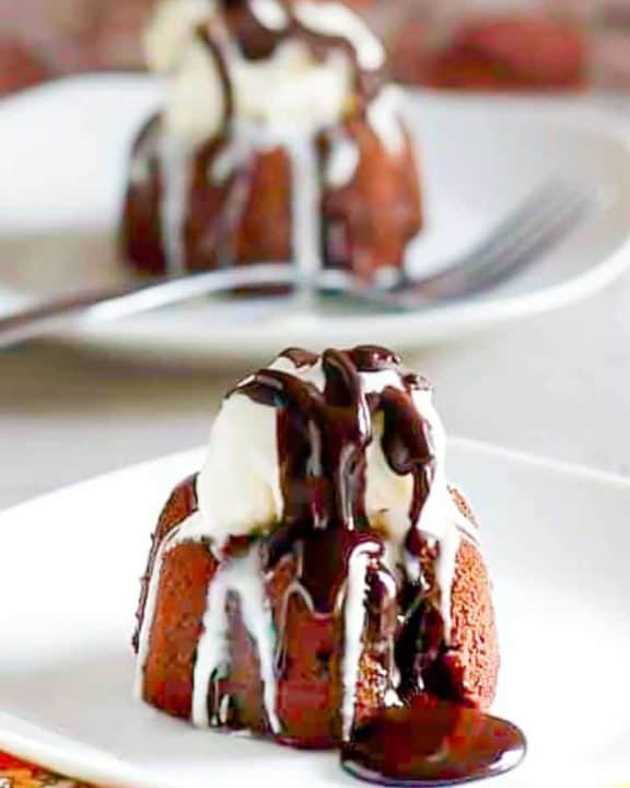 two triple chocolate meltdown cakes topped with ice cream and chocolate syrup