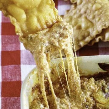 a pasta chip dipping into cheesy lasagna dip