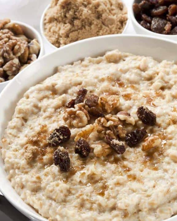 a bowl of oatmeal topped with raisins, walnuts, and brown sugar