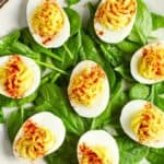 a plate of deviled eggs on top of fresh spinach leaves