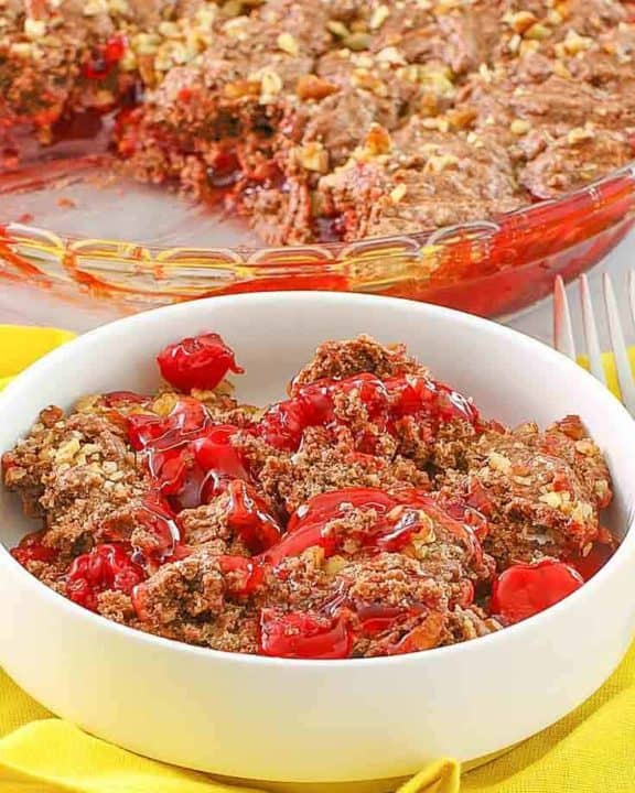 a bowl of cherry chocolate cobbler in front of the cobbler
