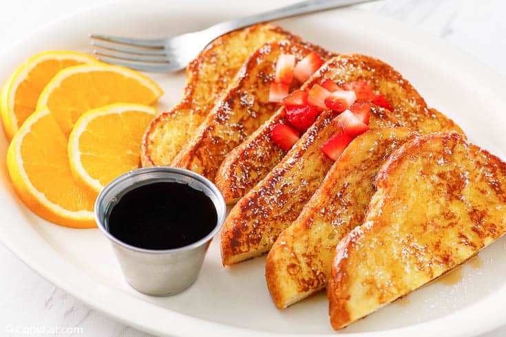 French toast with syrup, chopped strawberries, and orange slices