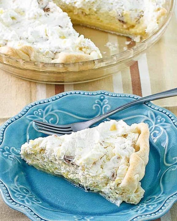 Homemade Furr's Pineapple Millionaire Pie on a blue plate next to the pie
