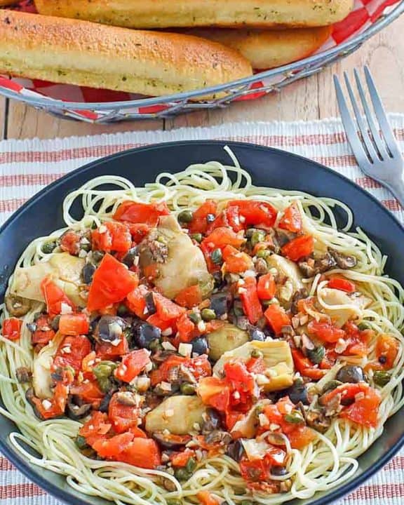 angel hair pasta with artichokes and a basket of breadsticks