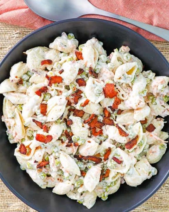pasta salad with bacon, peas, carrots, and ranch dressing in a black bowl