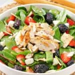 a salad with grilled chicken, berries, apples, and feta cheese