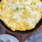 fluffy omelette in a skillet next to forks and napkins