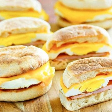 four homemade egg mcmuffins on a wood platter