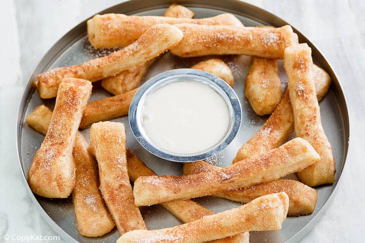 Homemade Dominos Cinnastix and icing dipping sauce on a round platter
