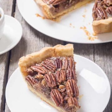 a slice of pecan pie on a white plate next to the pie