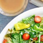 a bowl of homemade Luigetta's Italian salad dressing next to a salad